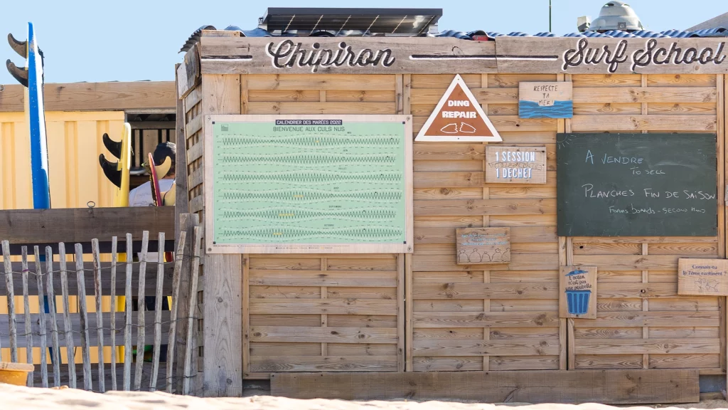 Photo du calendrier des marées en format XL sur la cabane de l'école de surf Chipiron Surf School sur la plage d'Hossegor
