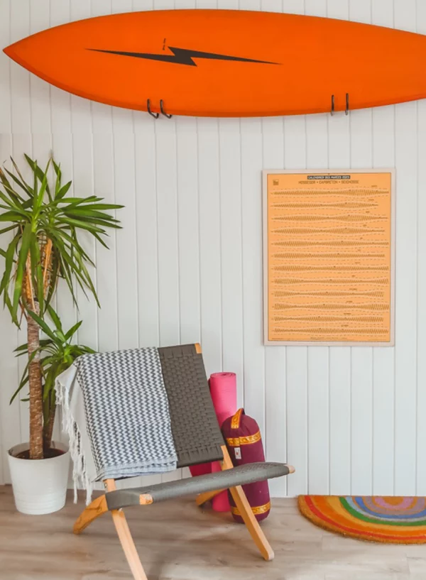 Photo of a surf-style interior decor with tide calendar and colorful surfboard